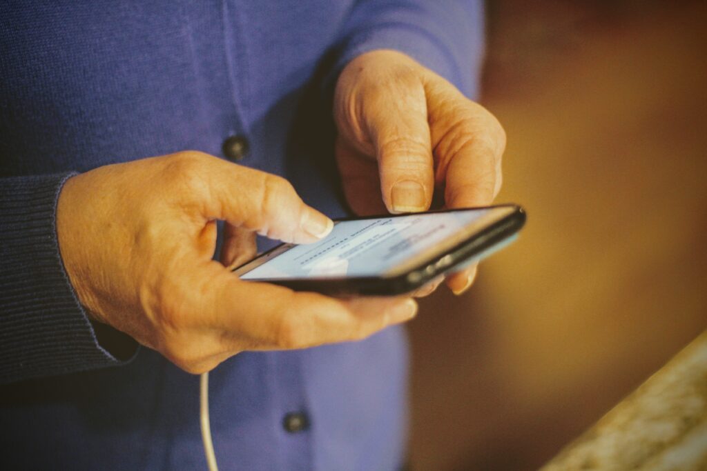 Hands of a senior woman texting on a cell phone.